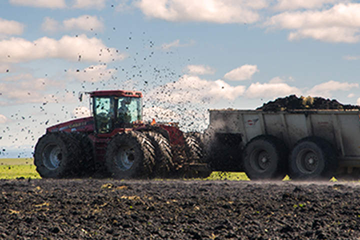 tractor spreading fertilizer over a field