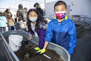 two children gardening in a raised planting container