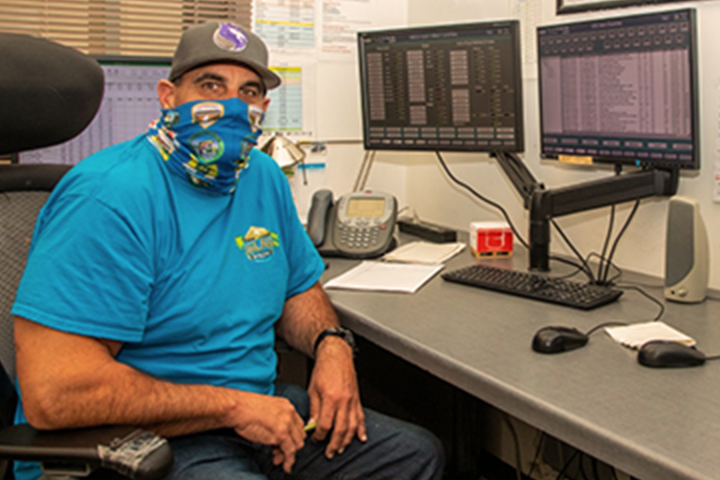masked technician sitting at computer workstation