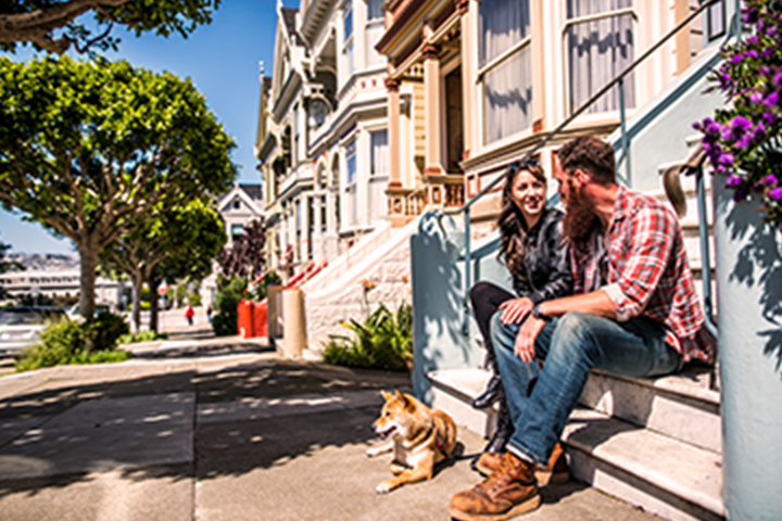 man, woman and their dog sitting on building's front steps