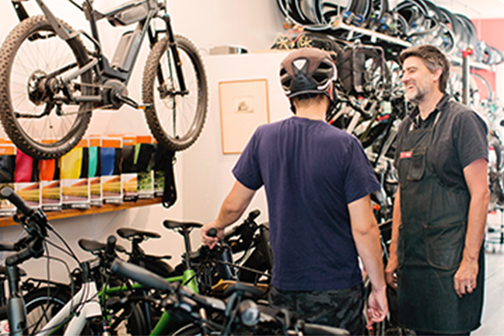 two men speaking inside a bicycle shop