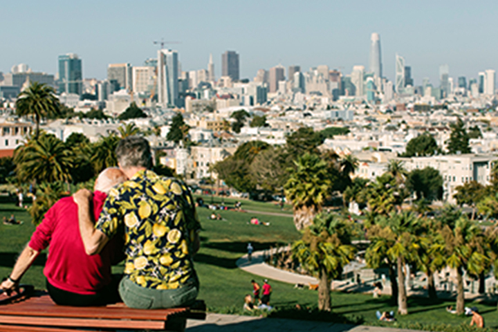 two men sitting on bench overlooking Dolores Park