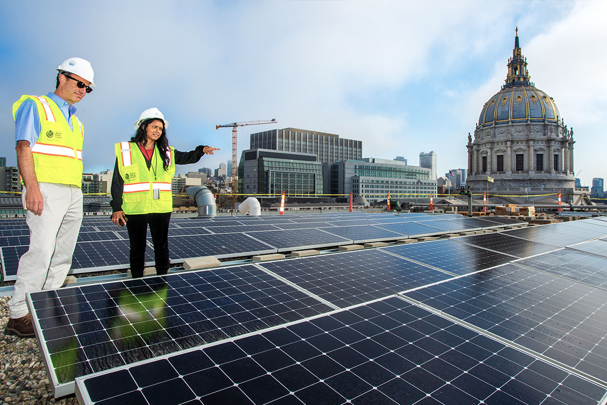 Two SFPUC employees look at solar panels at City Hall.