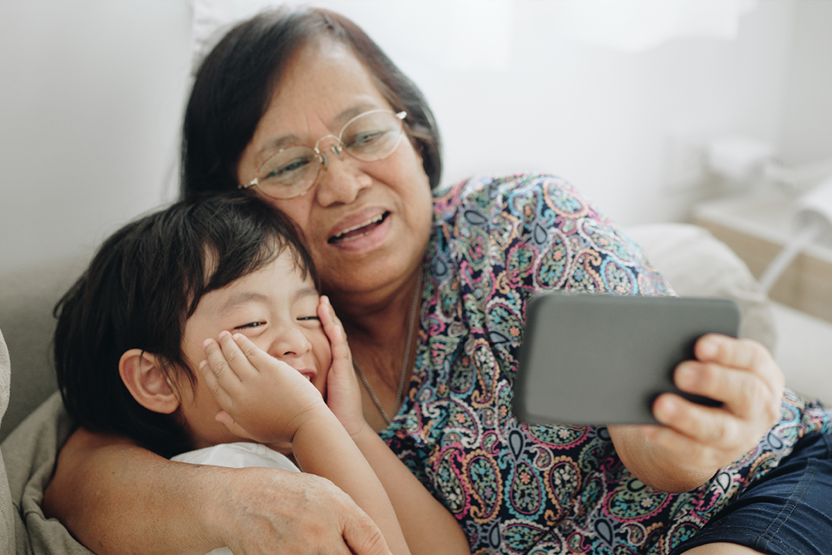 A grandmother and grandson look at a phone together.
