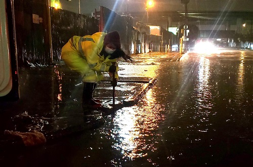 worker clearing a flooded street corner