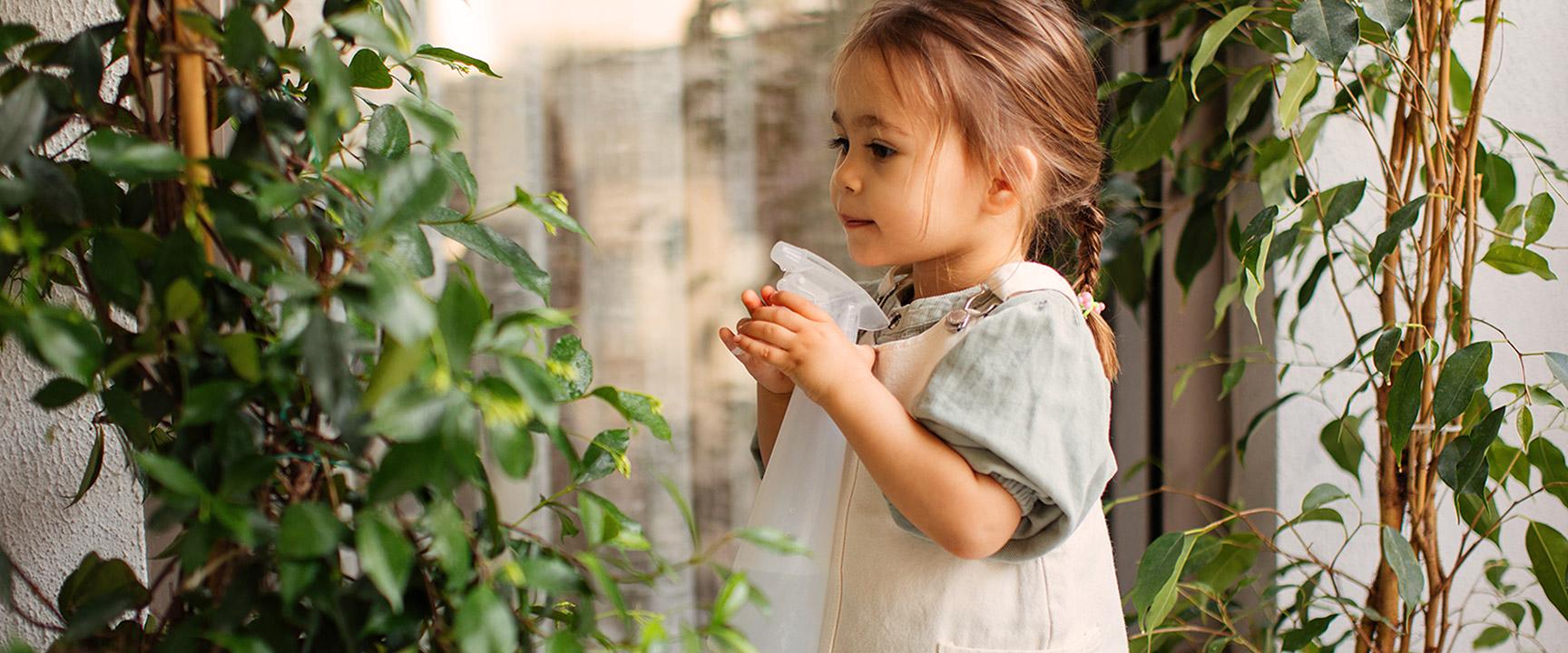 Young girl watering plant with a mister