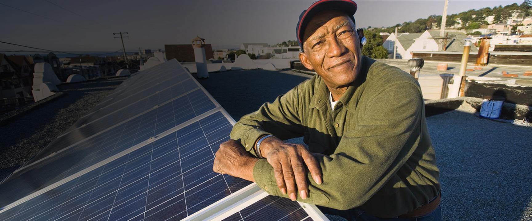 Man on roof leaning on solar panels