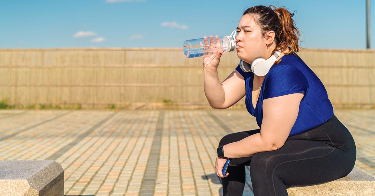 Woman in exercise clothes drinks from reusable water bottle