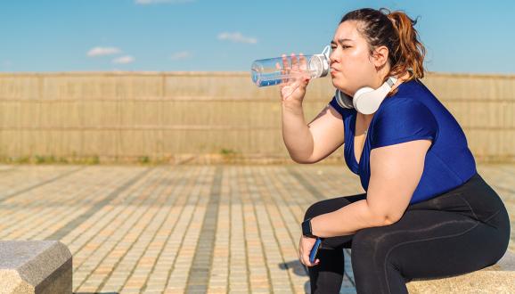 Woman sitting down drinking water.