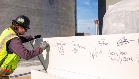 Will Crow, an inspector with the SFPUC’s Construction Management Team, signs the steel beam that will be the highest beam placed on the Biosolids Digesters Project (BDFP).